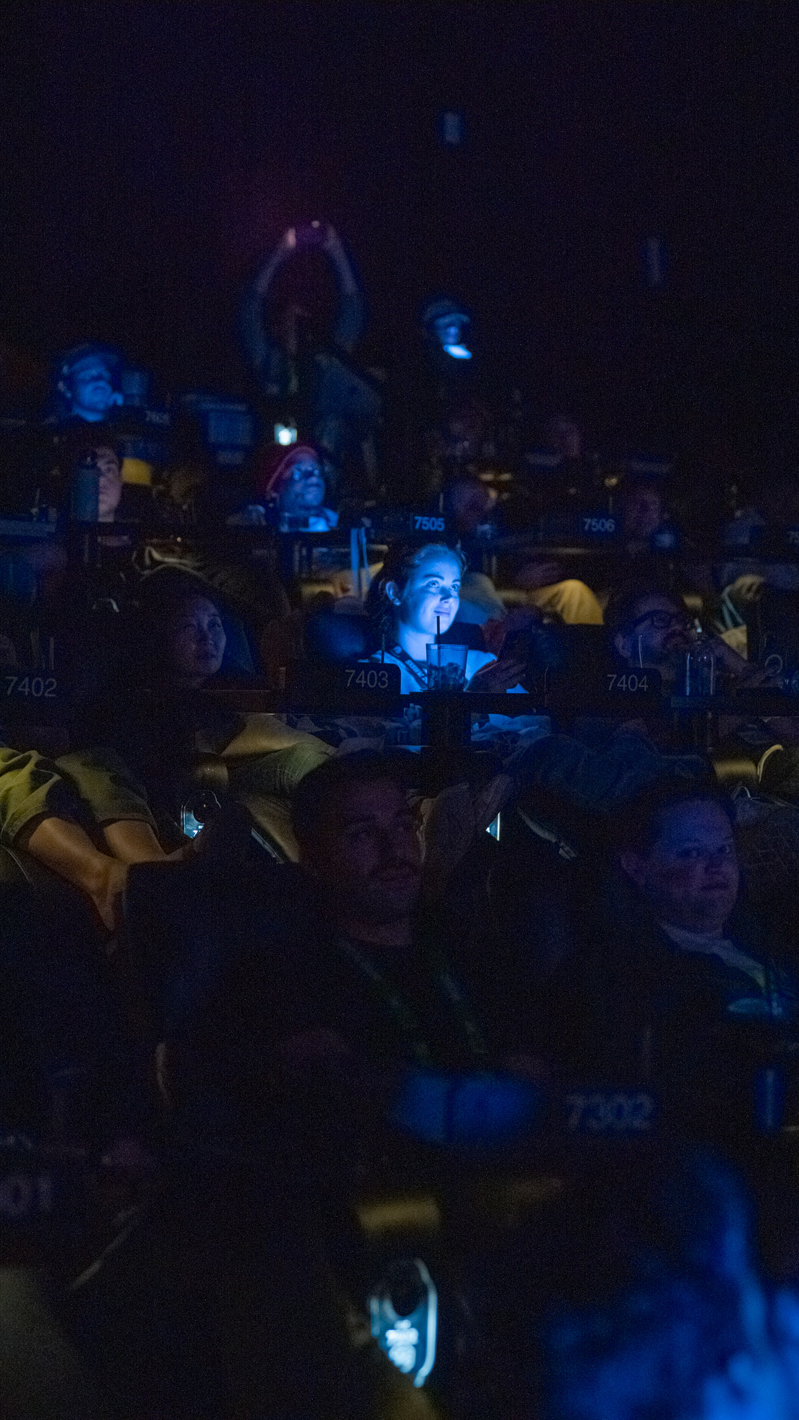 Audience in a theater, phones glowing
